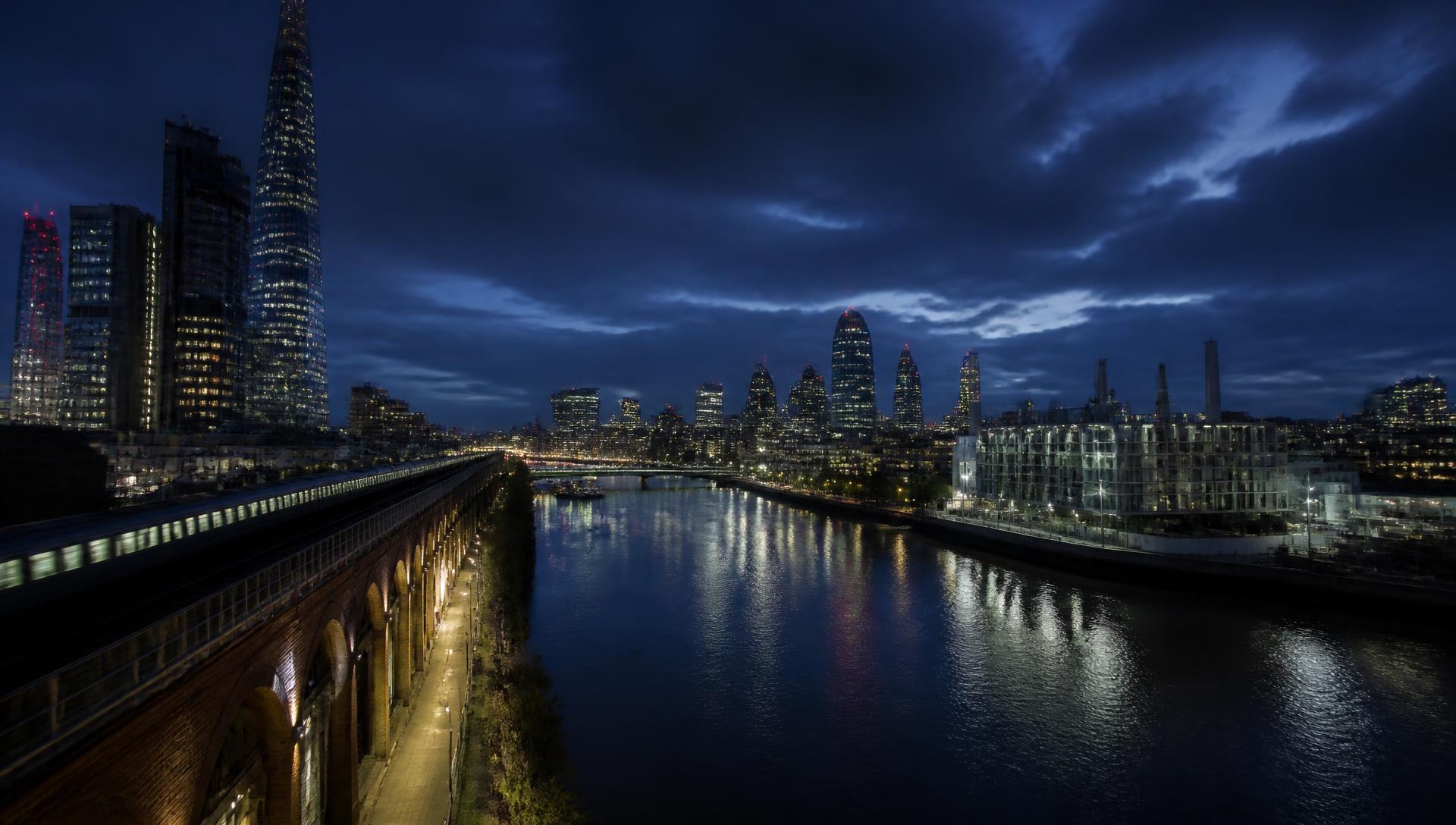 London skyline at twilight with the Thames, rail viaduct, towers and a riverside data centre